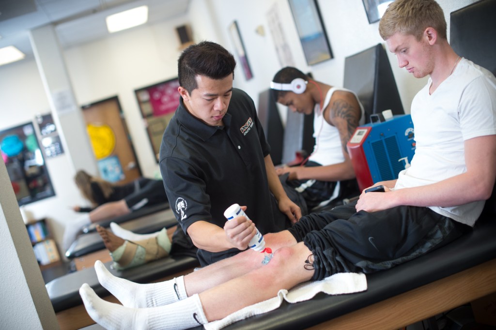 Athletic trainer uses a device on an athlete's leg