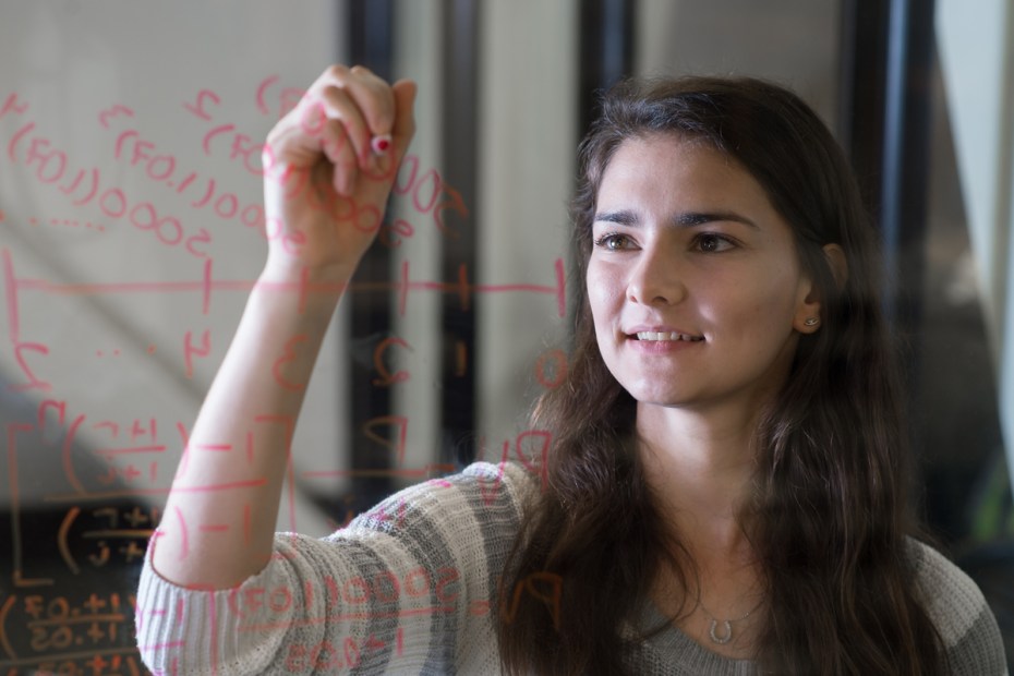 Student doing math on a clear dry-erase board.