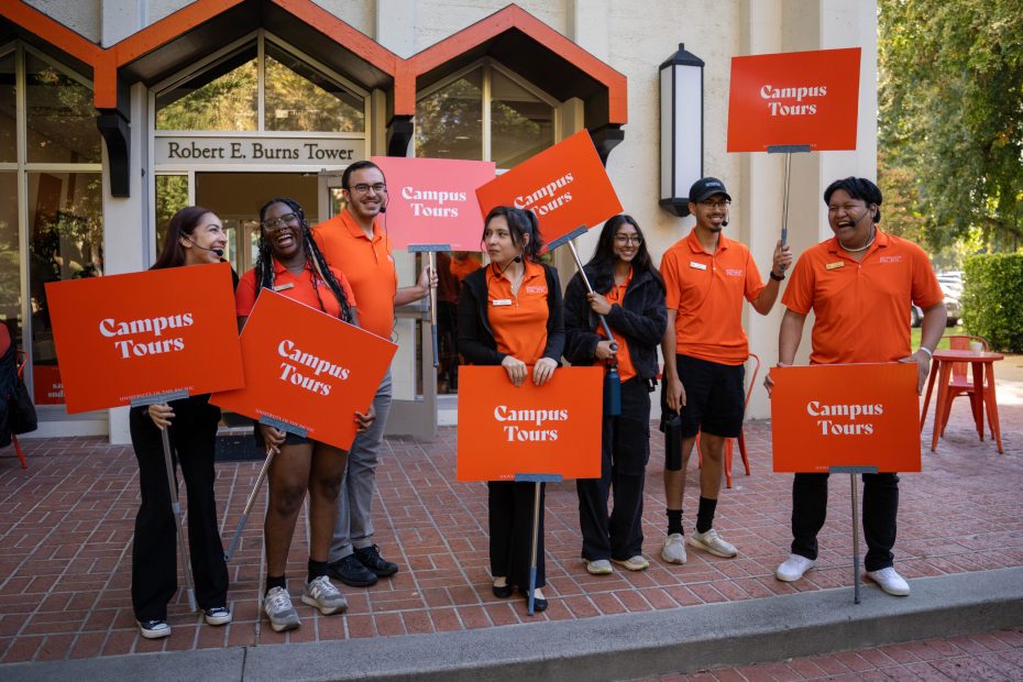 Student tour guides posing with their signs in front of Burns Tower.